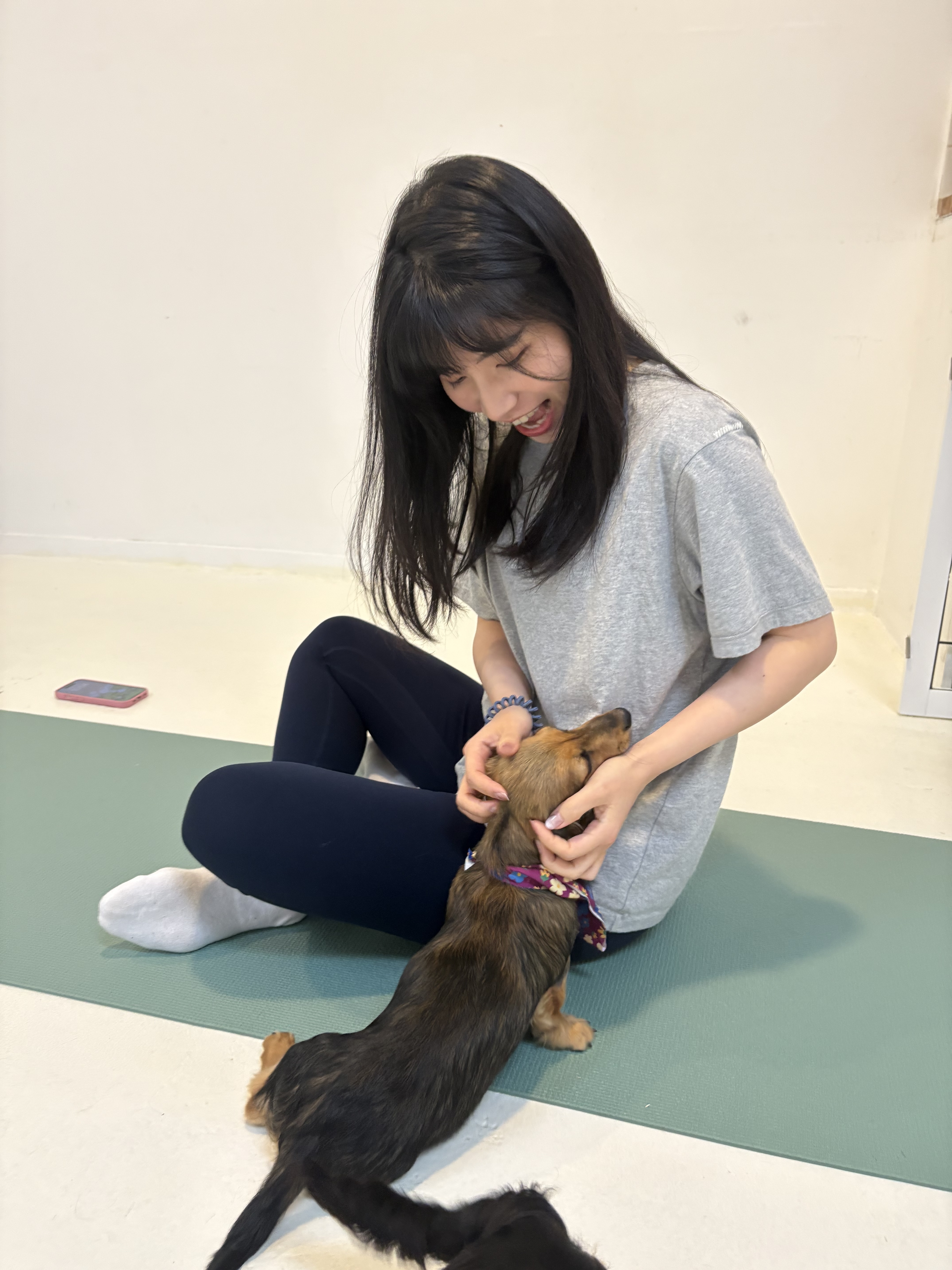 Christine sitting on a yoga mat and petting a dog