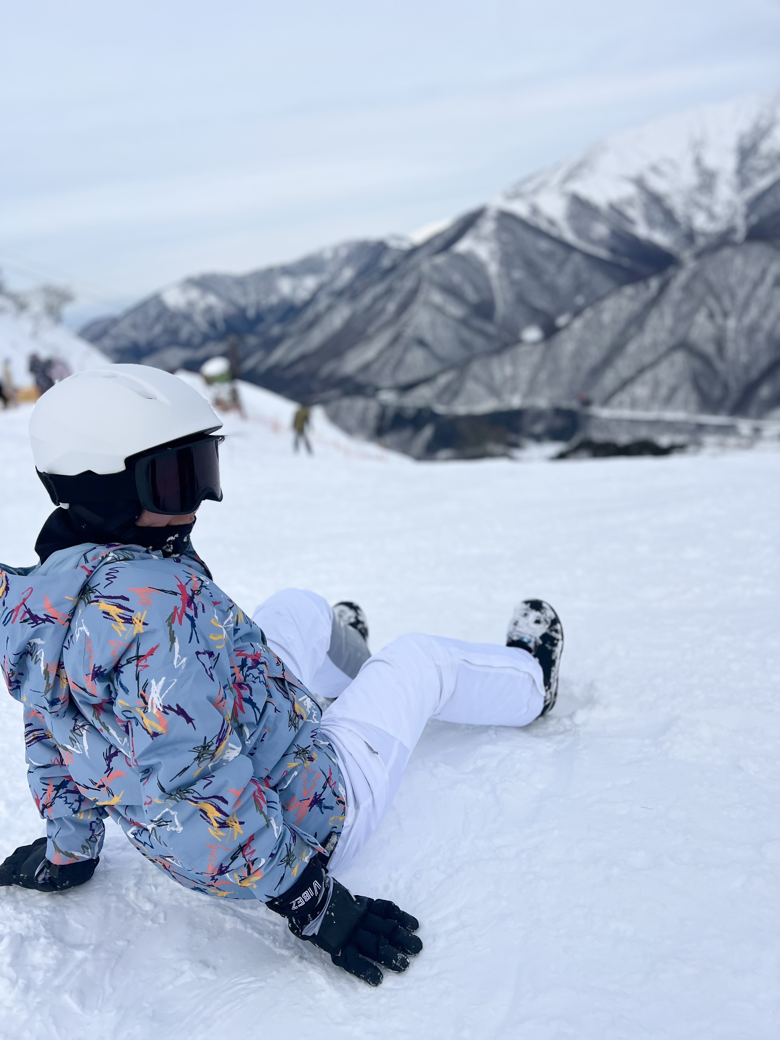 Christine in snowboarding gear taking a break on a snowy mountain slope